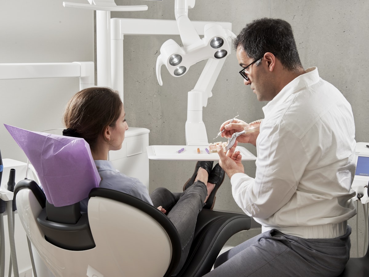 A friendly dentist talking with a happy, smiling patient in the dental chair